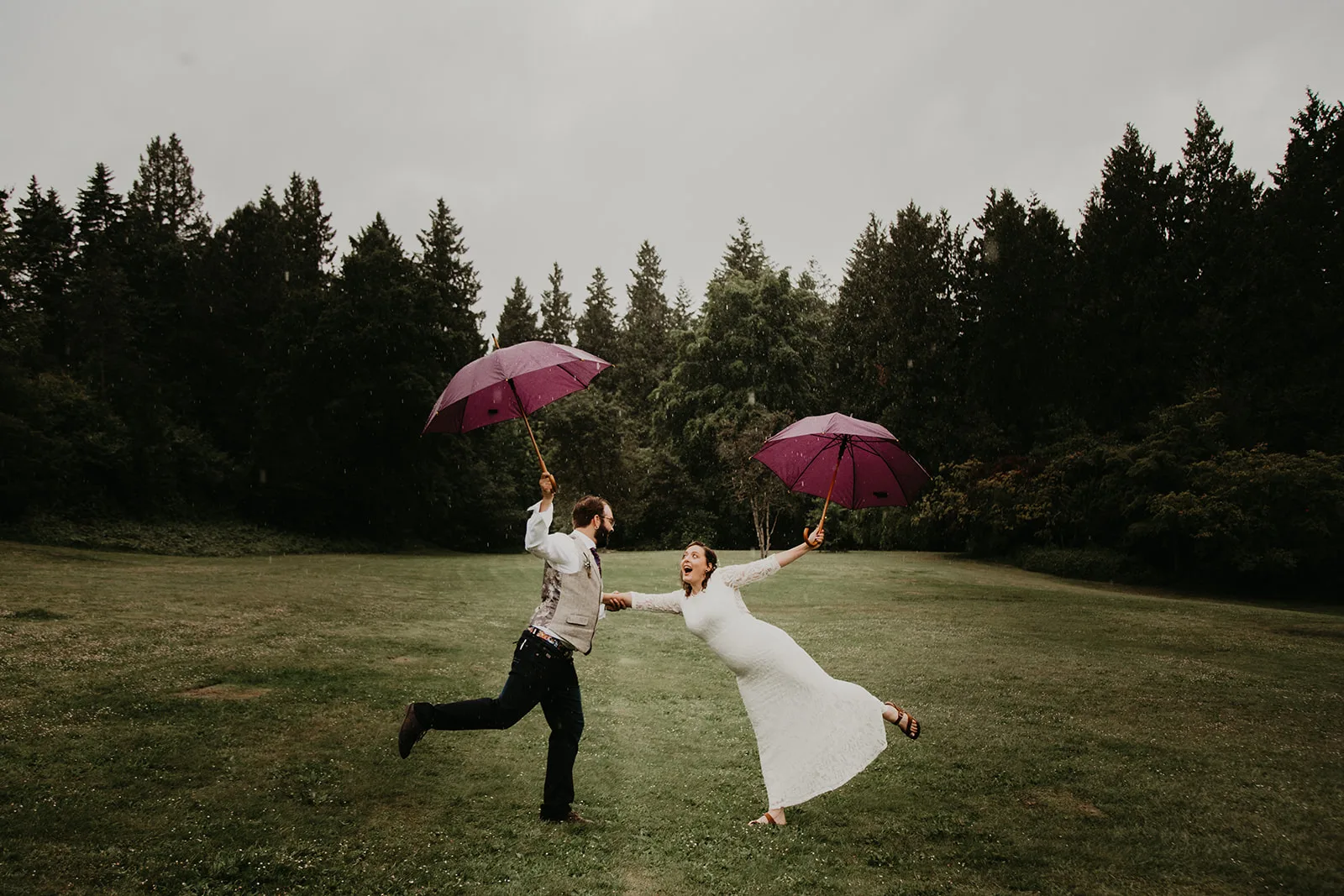 Bride and groom with umbrellas in Queen Elizabeth Park