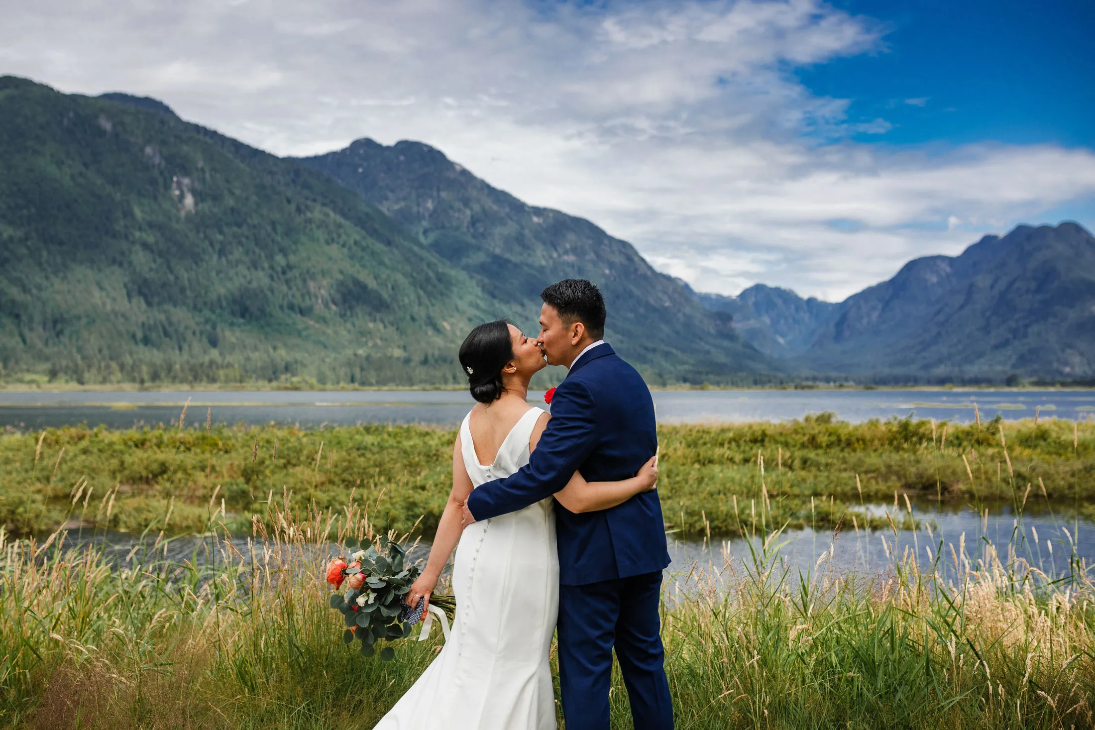 Newlywed couple kissing in front of mountains in Vancouver
