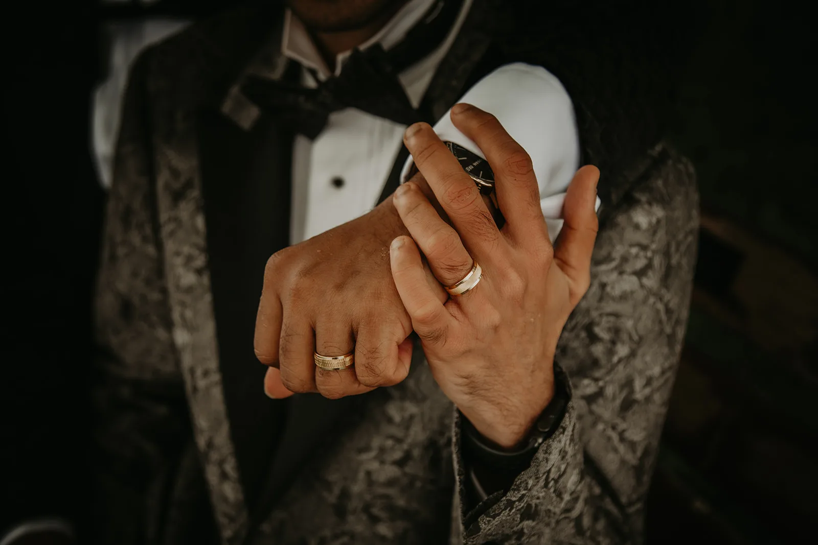 Two grooms holding hands and showing off their wedding rings