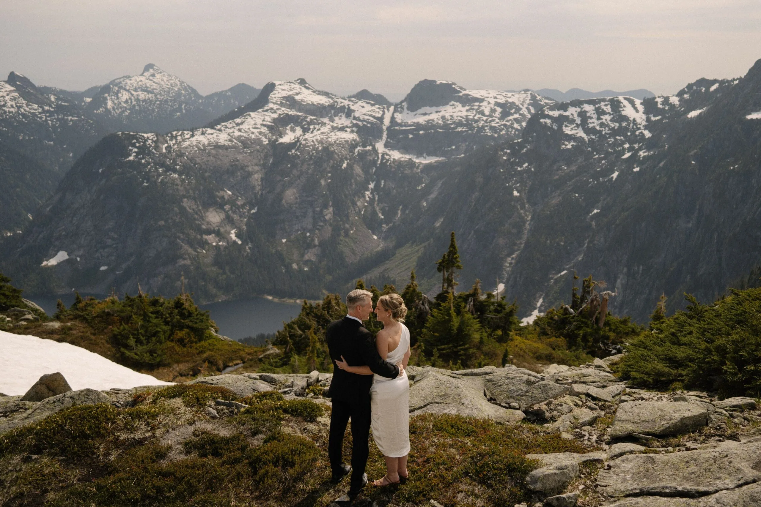 Newlyweds embracing on a mountaintop after their helicopter elopement with Young Hip & Married
