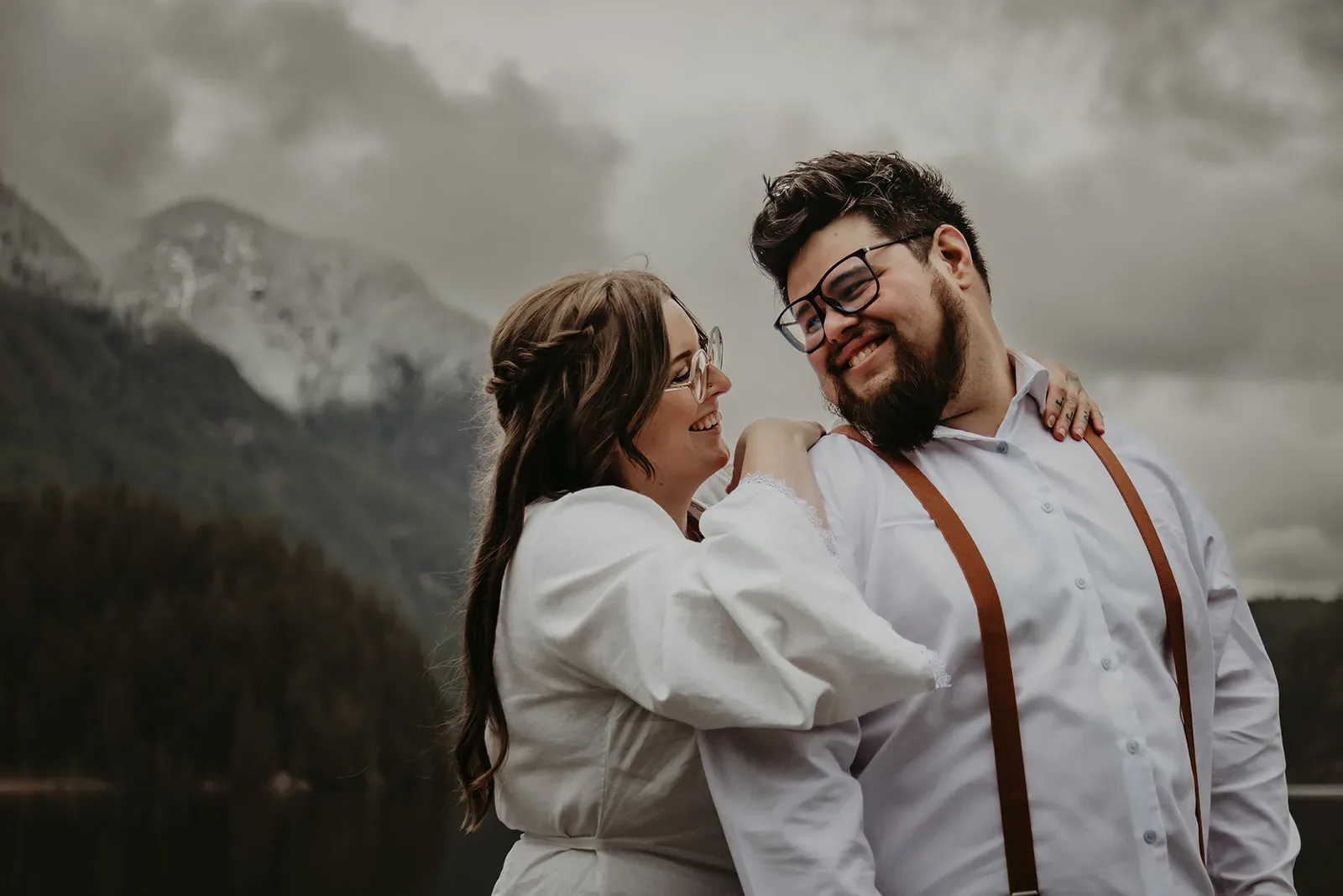 Newlywed couple smiling at each other in front of misty mountains after their Vancouver elopement