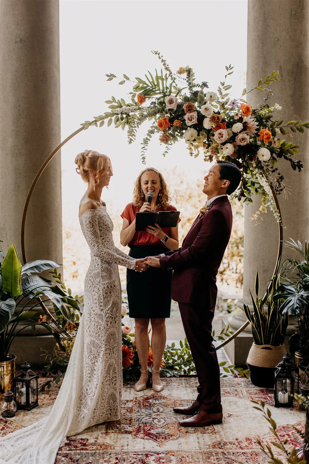 Officiant Jane leading a ceremony for Paige and Corey in front of a floral arch