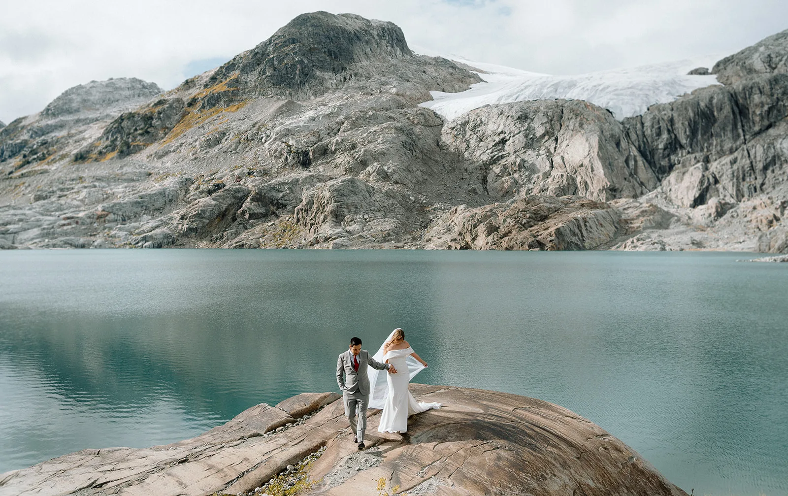 Newlywed couple walking along a mountain after their helicopter elopement with Young Hip & Married