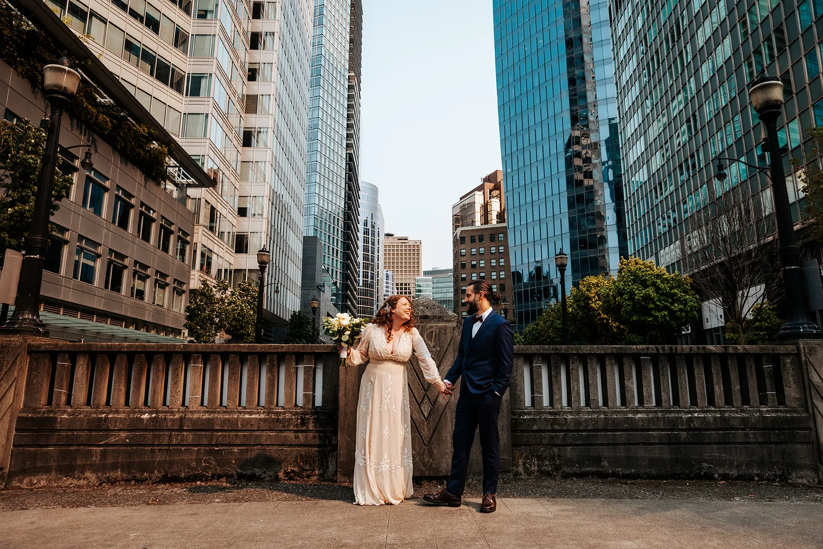 Newlywed couple posing between high rise buildings in downtown Vancouver