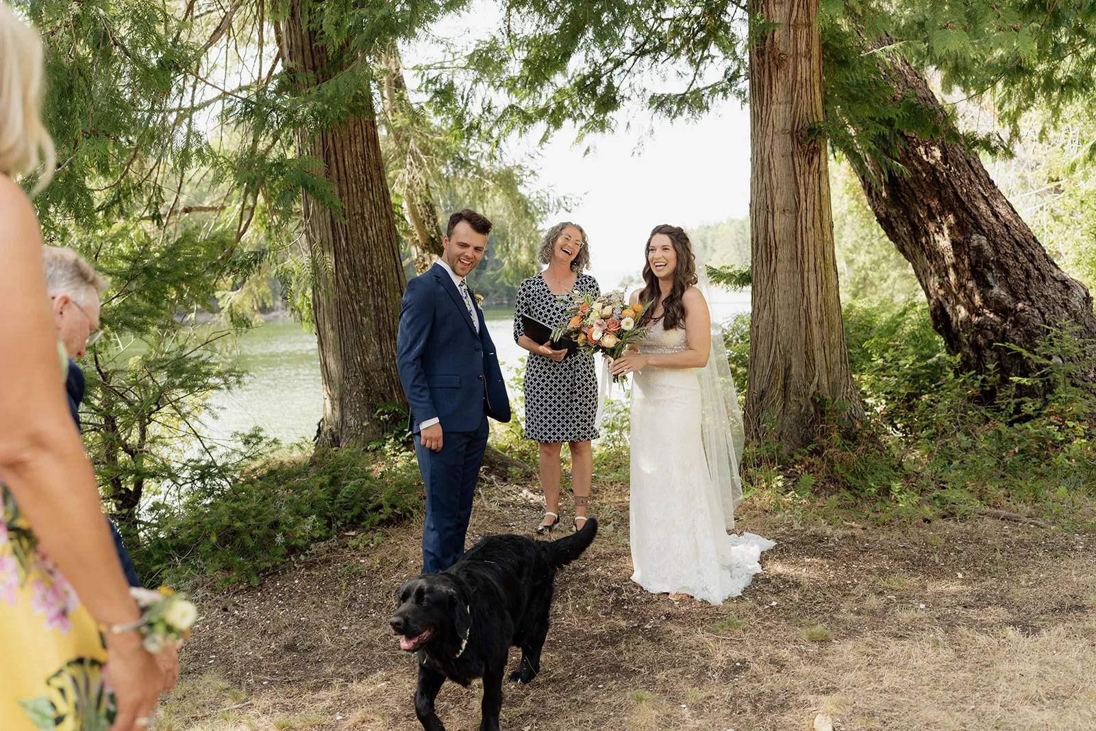 Officiant Amanda laughing with the bride and groom as their dog interrupts the ceremony