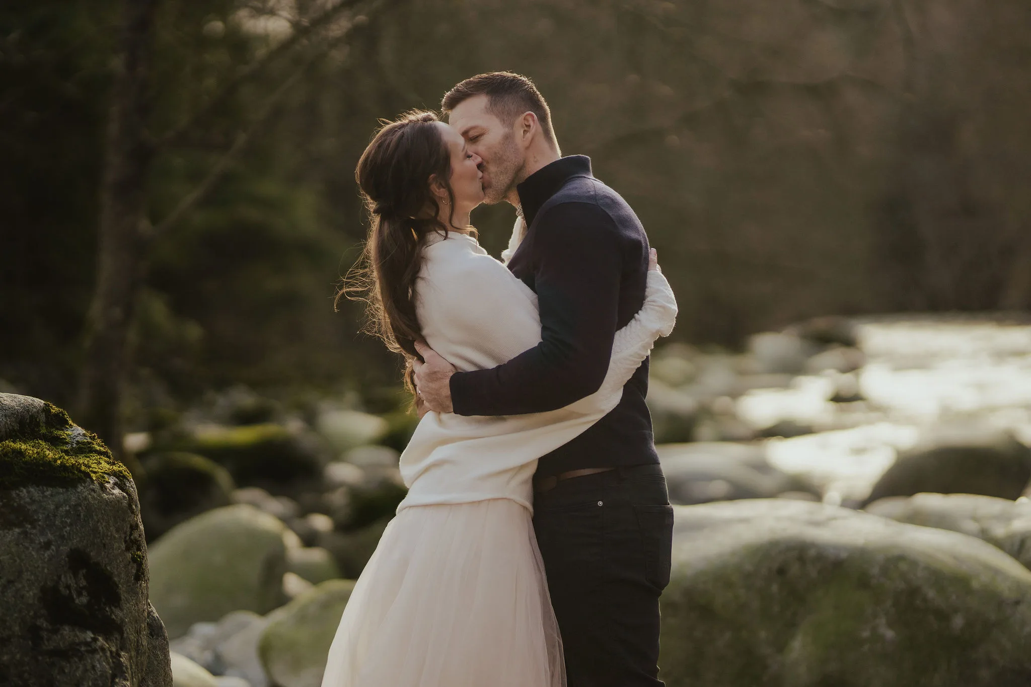 Newlywed couple kissing on the banks of a river