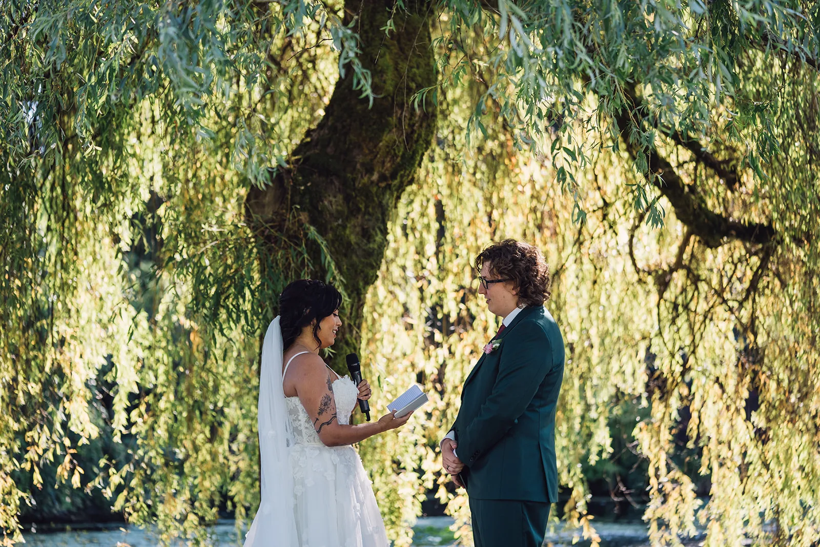 Bride and groom exchanging their vows under a willow tree