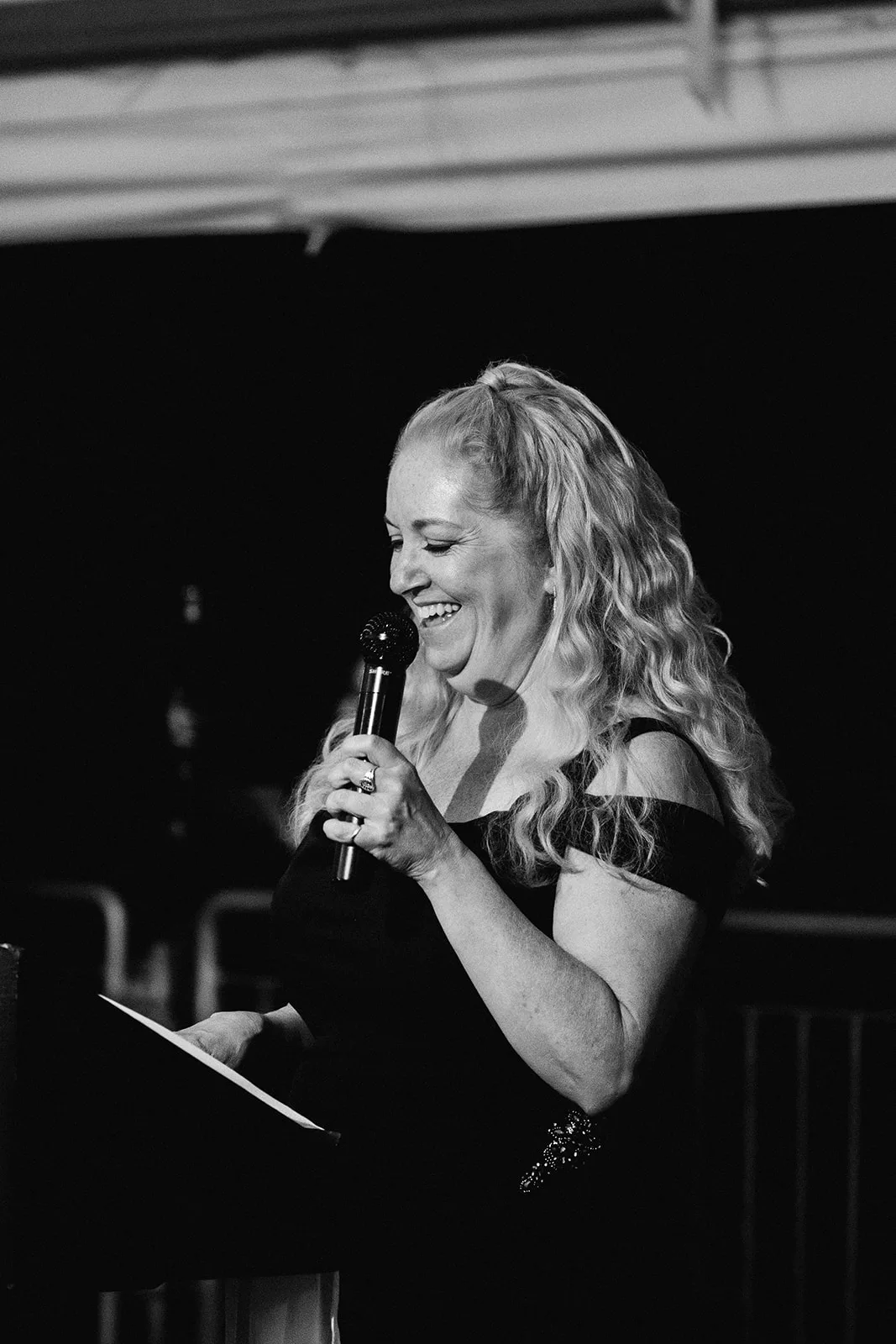 Mother of the bride wedding speech, mom smiling holding a mic in black and white