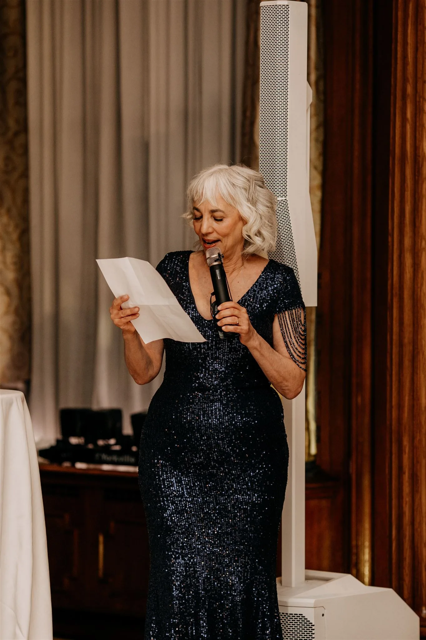 Mother of the bride wedding speech, mom holding mic and piece of paper in blue dress