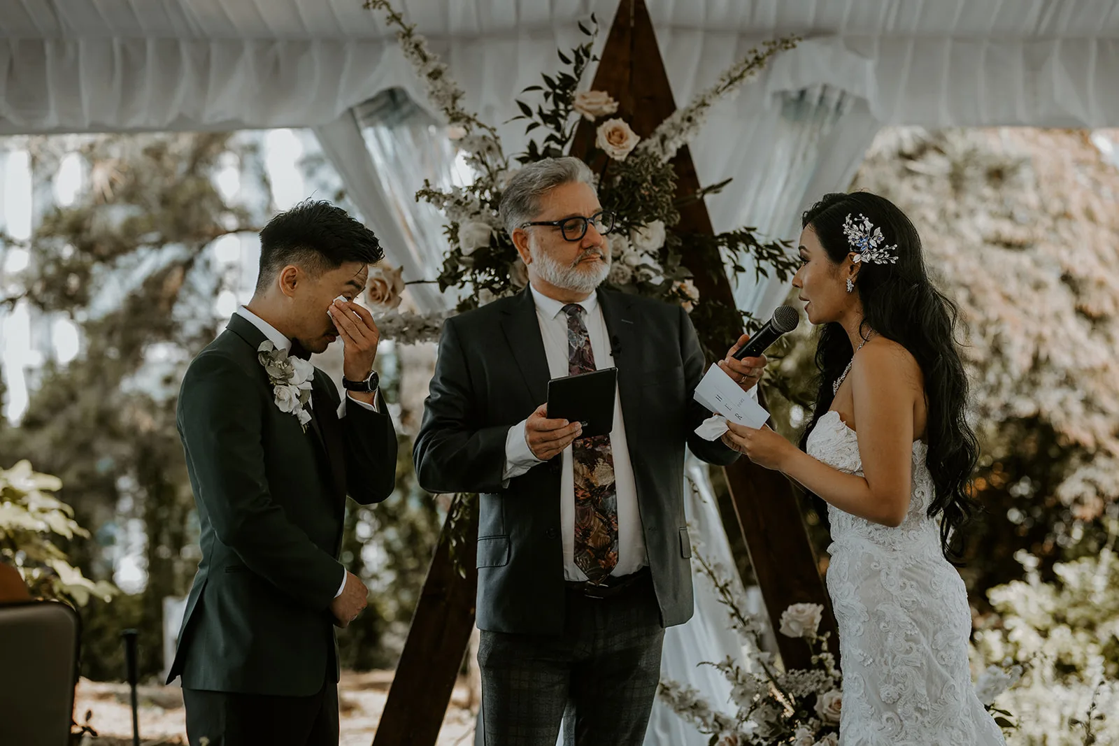 Officiant Daniel holding the microphone for Meg as she says her vows to Andy during their ceremony, Isle and Oak Photography